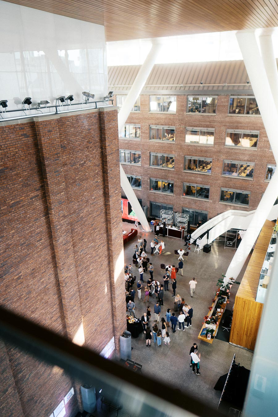 Overhead view of guests mingling in the spacious atrium of Ricarda’s, Toronto, during the Toronto Prep Forever Launch Party with visible brick walls and event setup.