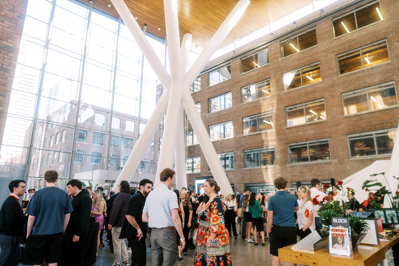 Candid crowd of guests networking in the sunlit atrium at Ricarda’s, Toronto, during the Toronto Prep Forever Launch Party, with modern architecture visible.