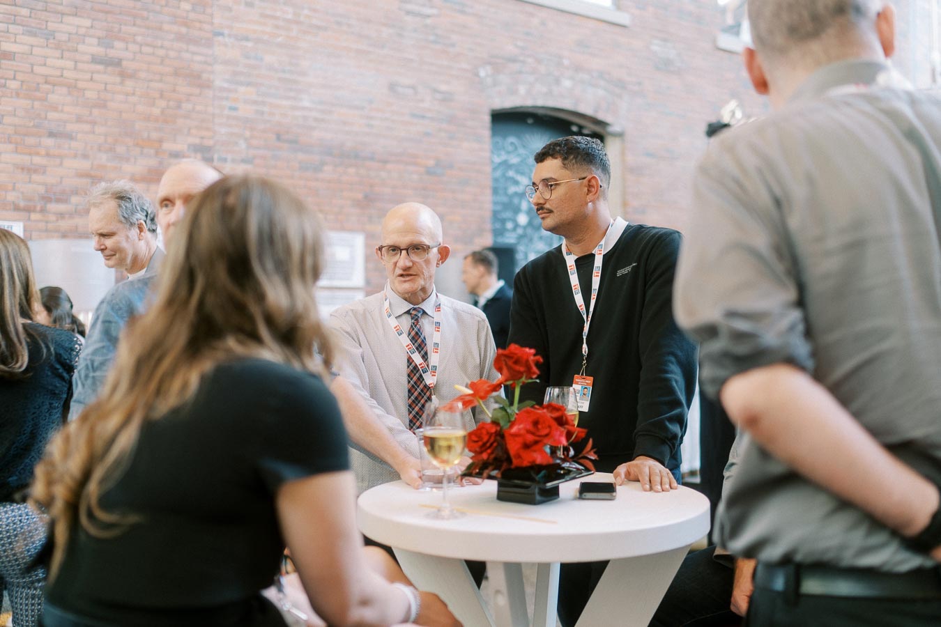 Group of guests networking around a white cocktail table with red flowers at the Toronto Prep Forever Launch Party at Ricarda’s, Toronto.