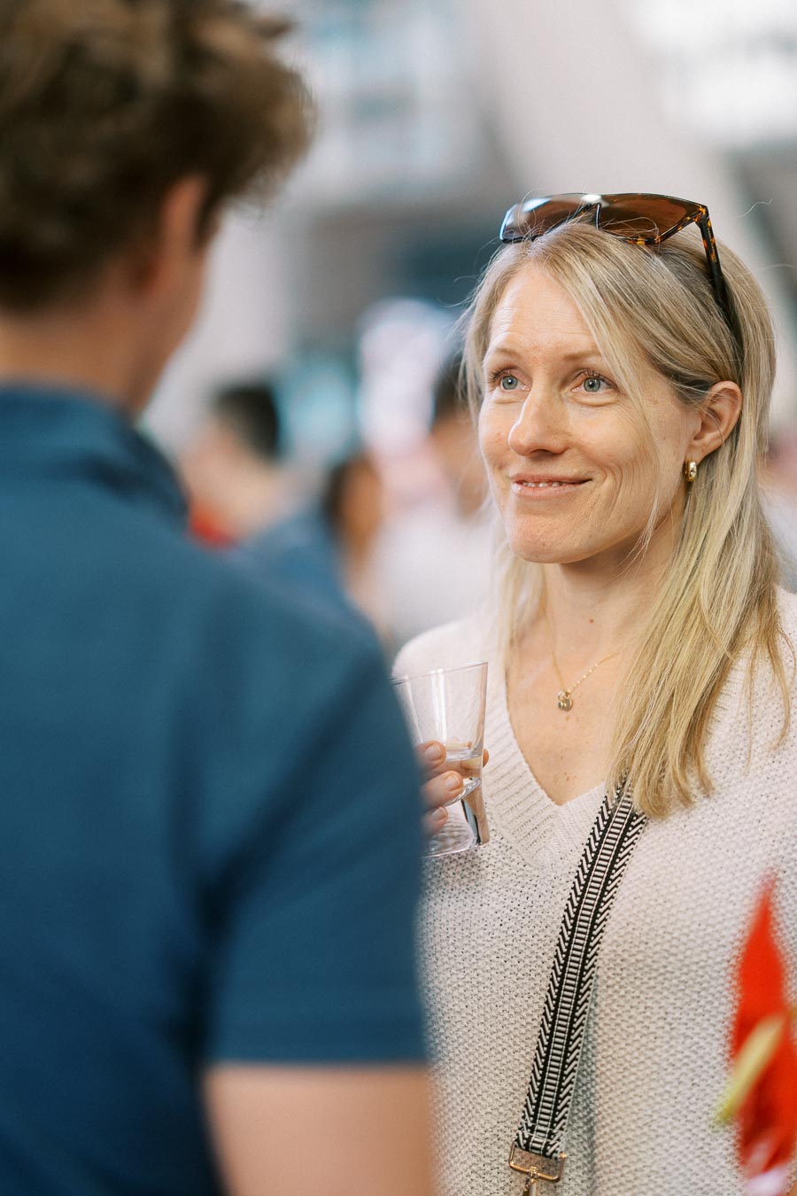A woman with blonde hair and sunglasses on her head holds a drink while speaking with another guest at the Toronto Prep Forever Launch Party at Ricarda’s.