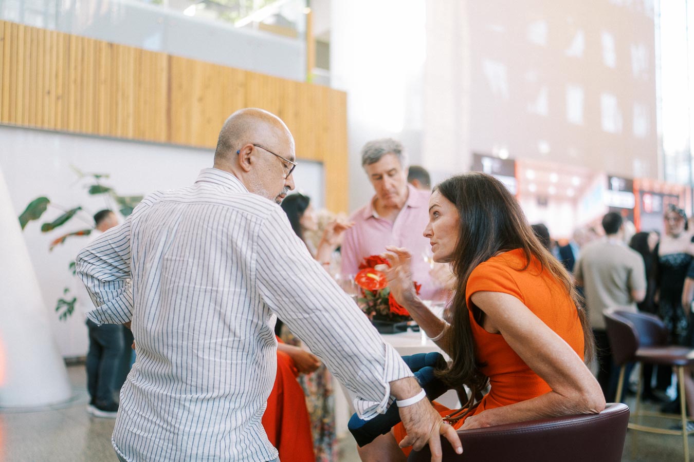 Two guests in animated conversation seated at a table with red floral decor at the Toronto Prep Forever Launch Party at Ricarda’s in Toronto.