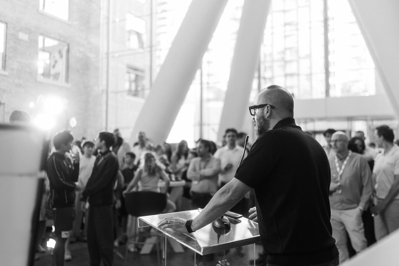 A man speaks at a podium to a diverse audience inside The Atrium at Ricarda’s in Toronto during the Toronto Prep Forever Launch Party.