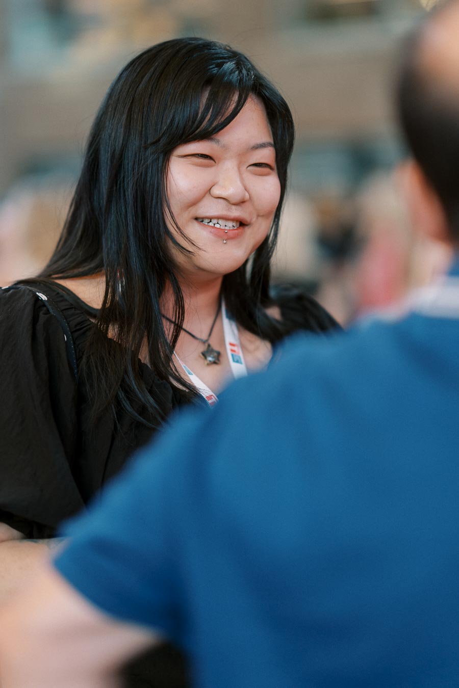 A guest with long dark hair and a star necklace smiles while engaging in conversation at the Toronto Prep Forever Launch Party at Ricarda’s.