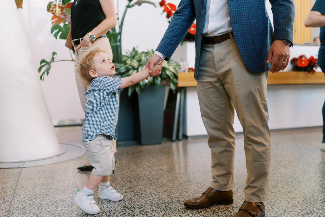A small child in a blue checkered shirt holds hands with an adult in a blue blazer at Ricarda’s, Toronto, during the Toronto Prep Forever Launch Party.