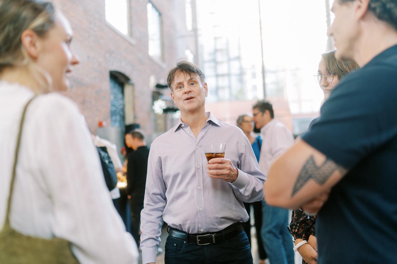 A man holding a drink converses with a group of guests at the Toronto Prep Forever Launch Party at Ricarda's Restaurant, Toronto.