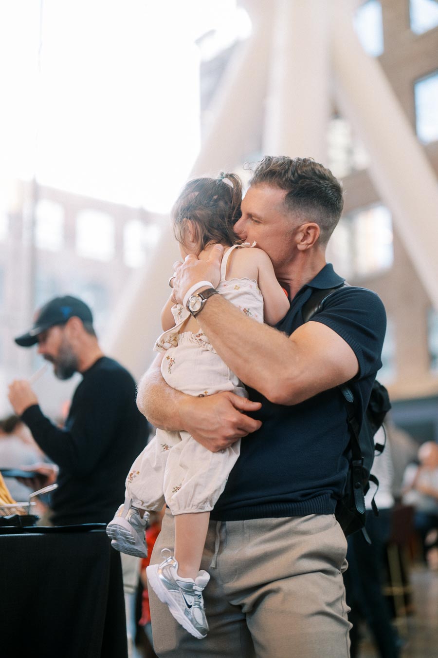 A father embraces his young daughter in a bright, modern atrium during the Toronto Prep Forever Launch Party at Ricarda’s, Toronto.