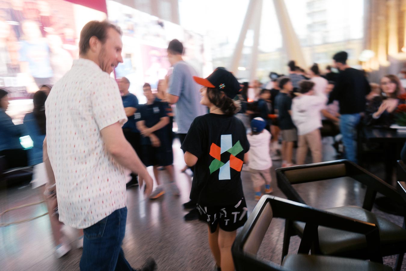 A candid photo of a man and a child in Toronto Prep School branded clothing walking through a lively crowd at Ricarda’s event space in Toronto.