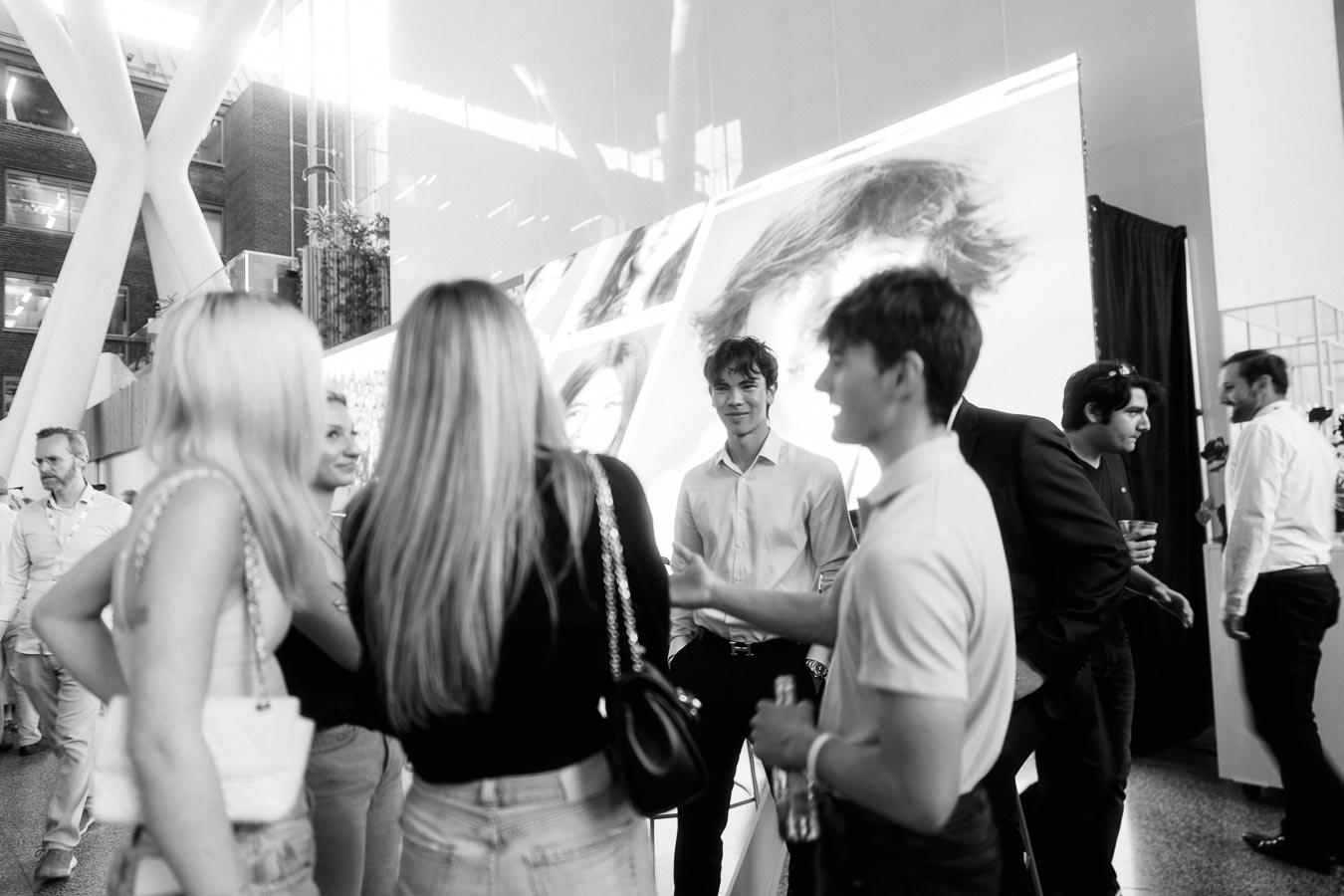 A group of young adults and guests converse in a modern atrium during the Toronto Prep Forever Launch Party at Ricarda’s in Toronto.