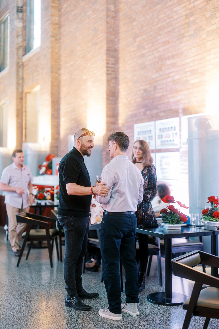 Three guests converse at Ricarda's in Toronto during the Toronto Prep Forever Launch Party, with floral arrangements and school signage visible in the background.