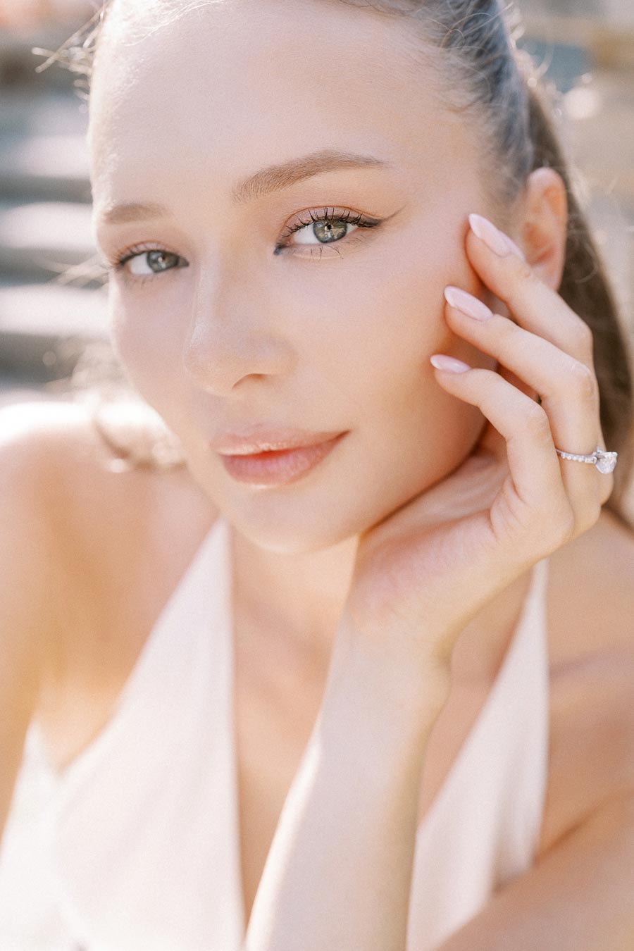 Bride-to-be Anastasiia close-up with hand near face, engagement ring visible.
