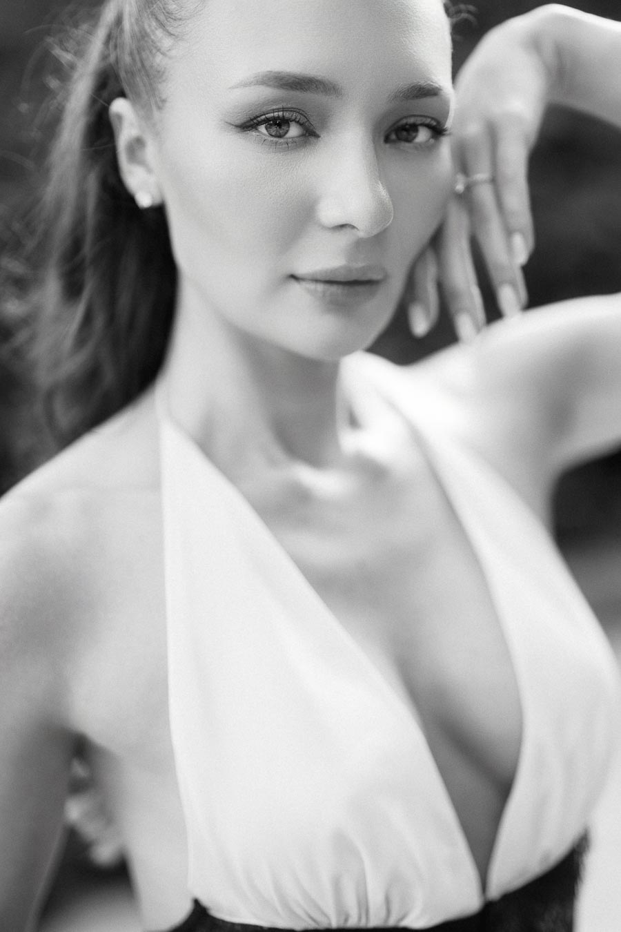 Close-up black and white portrait of Anastasiia with hand near face, engagement ring visible.