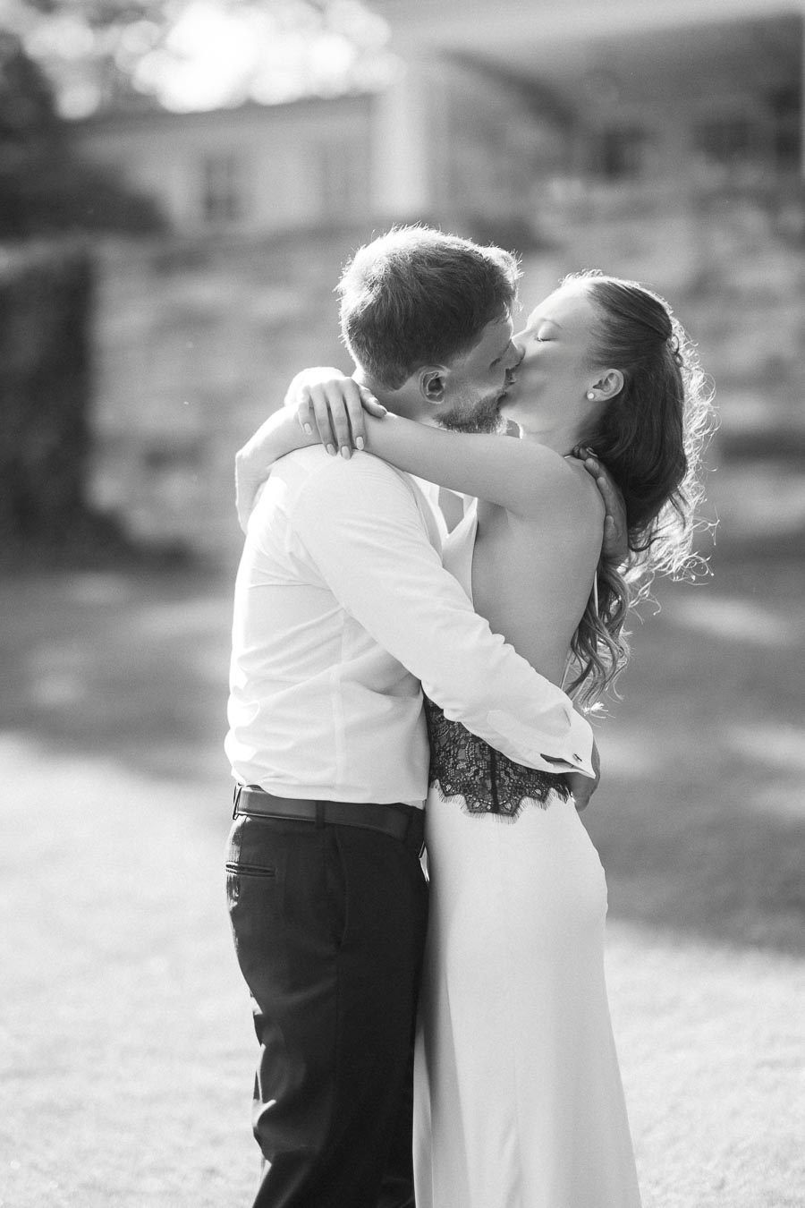 Anastasiia and Petr kissing and embracing on a lawn in black and white.