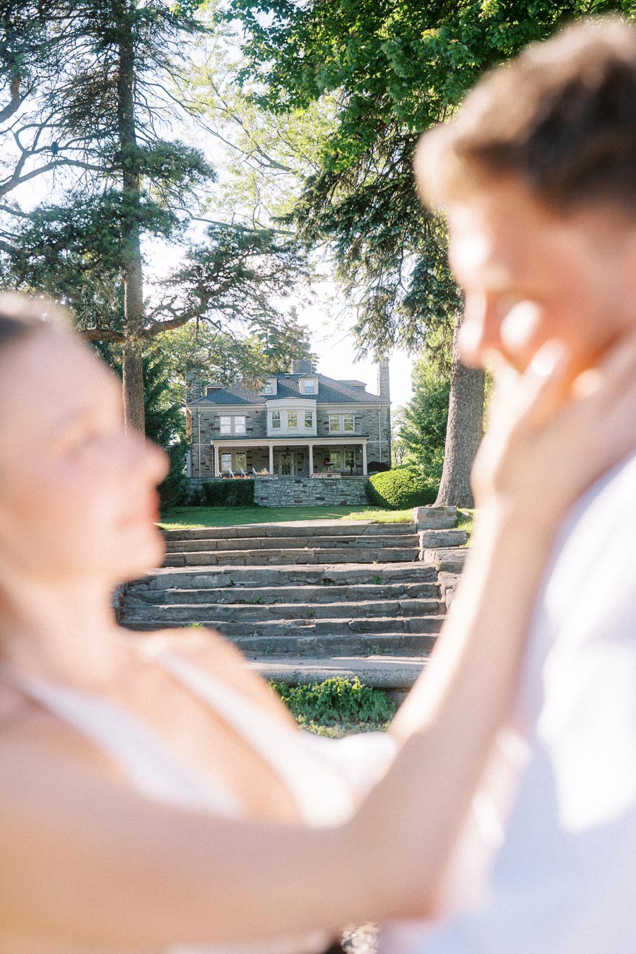 Out-of-focus engaged couple in foreground, Paletta Mansion and stone steps in sharp background.