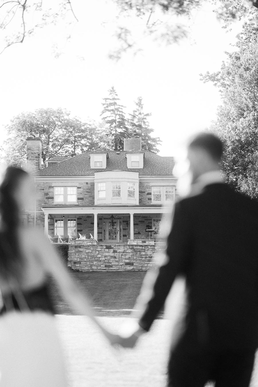 Blurred engaged couple holding hands with Paletta Mansion in focus behind them.