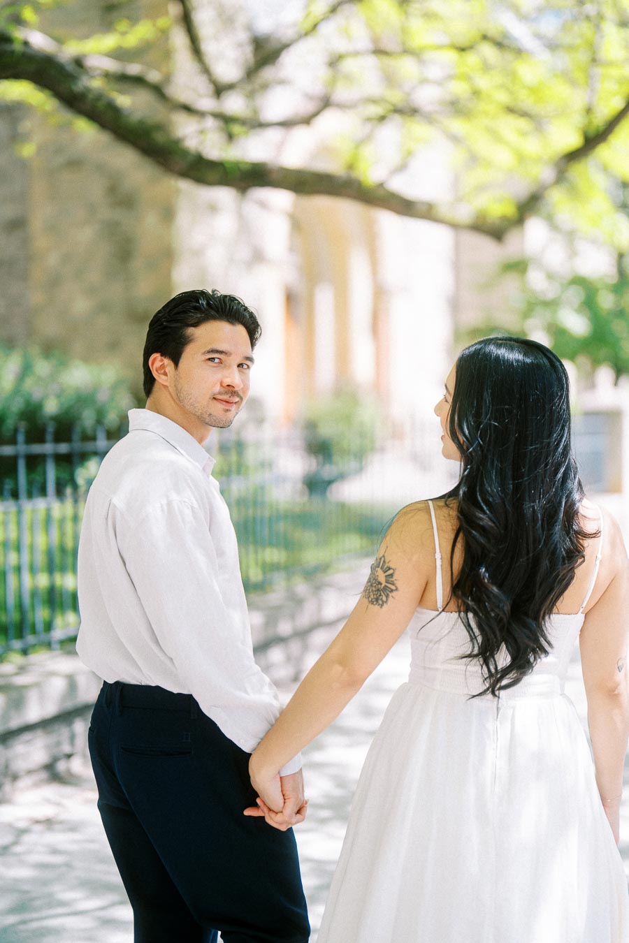 Cassie and Gabriel holding hands while walking on a shaded sidewalk in downtown Toronto during their engagement session.