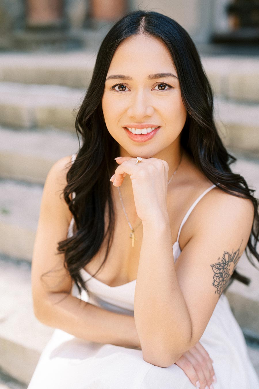 Cassie smiling and sitting on outdoor stone steps during her engagement session in downtown Toronto.