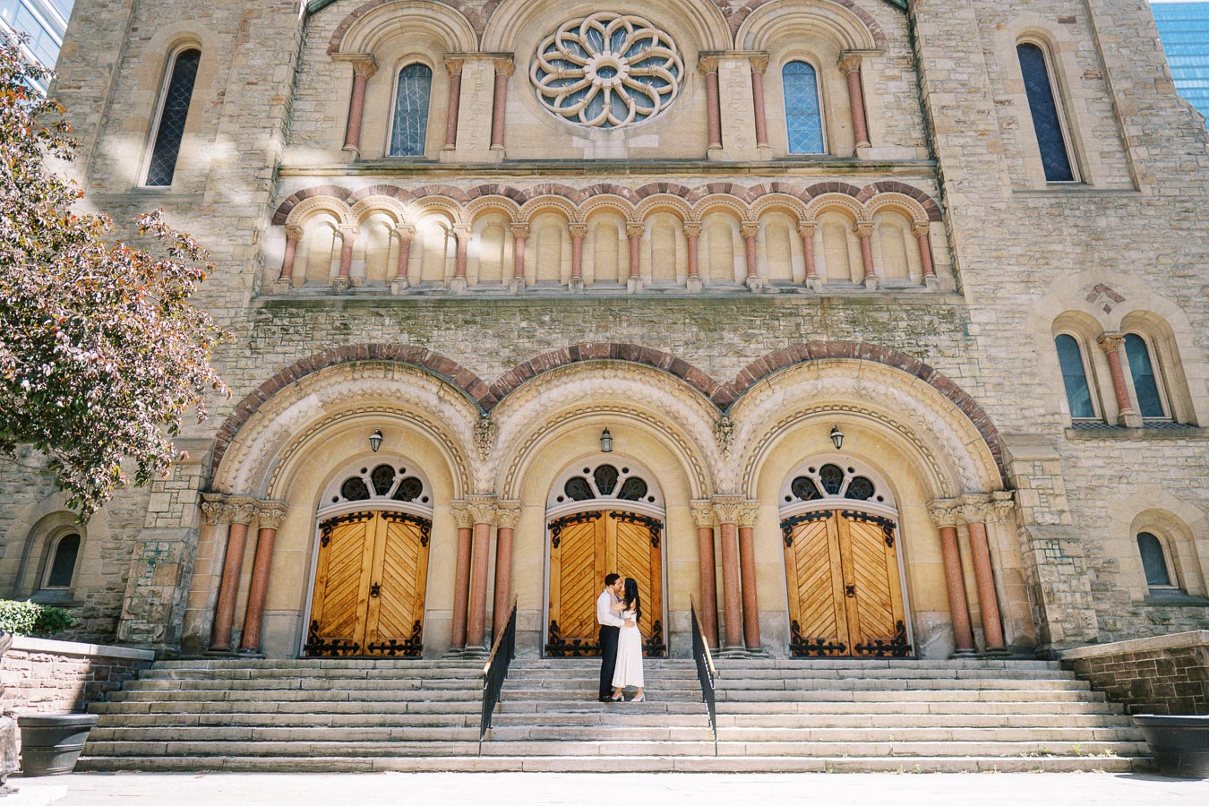 Cassie and Gabriel standing together on the front steps of St. Andrew’s Presbyterian Church in downtown Toronto during their engagement session.