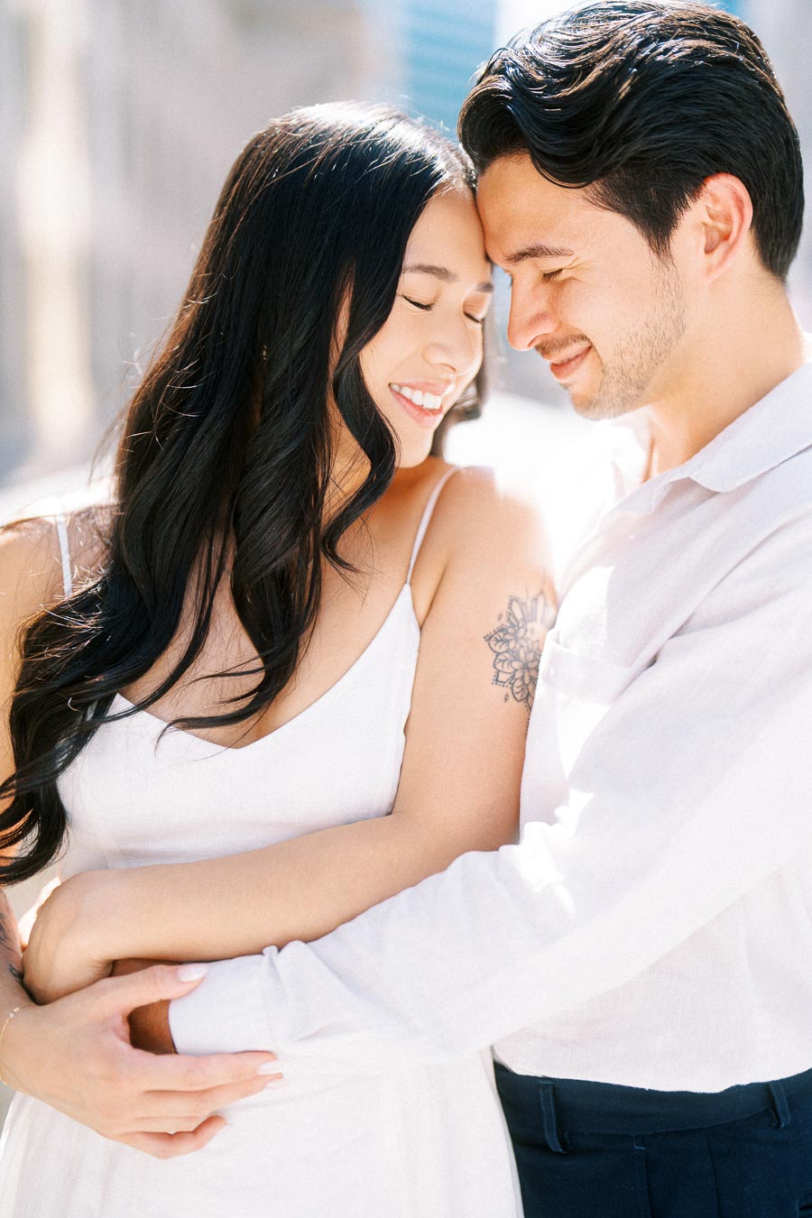 Cassie and Gabriel smiling with their eyes closed, embracing closely during their engagement photoshoot in downtown Toronto.