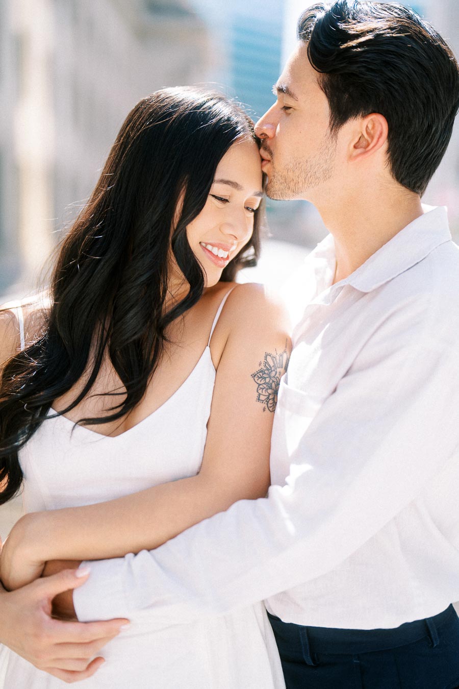 Cassie and Gabriel embrace closely as Gabriel kisses Cassie's forehead during their engagement session in downtown Toronto.