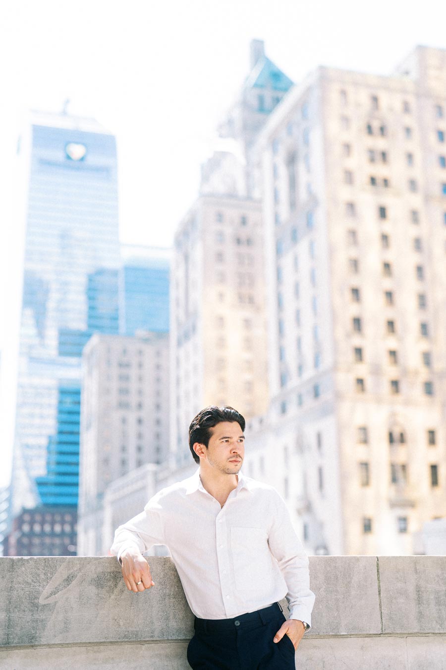 Gabriel stands by a stone railing in downtown Toronto with tall buildings and city architecture in the background.