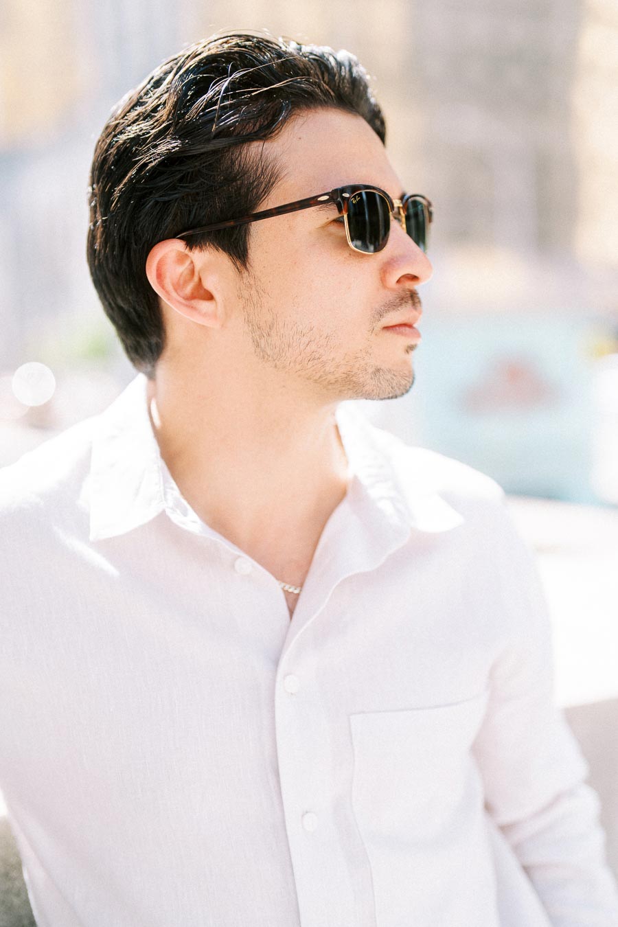 Gabriel wearing sunglasses and a white shirt, looking off to the side during an engagement photoshoot in downtown Toronto.