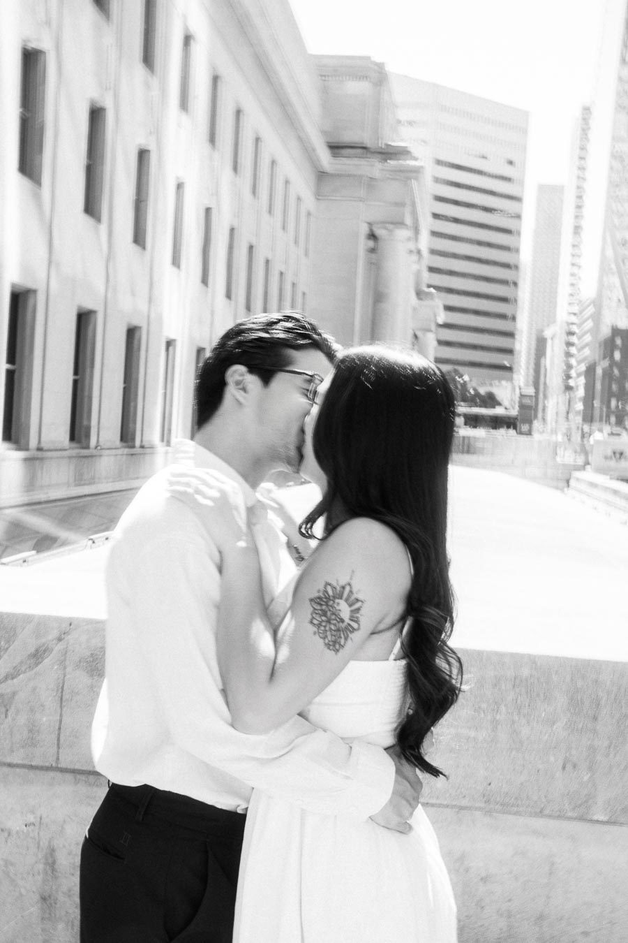 Cassie and Gabriel kissing outdoors during their engagement session, with downtown Toronto buildings in the background.