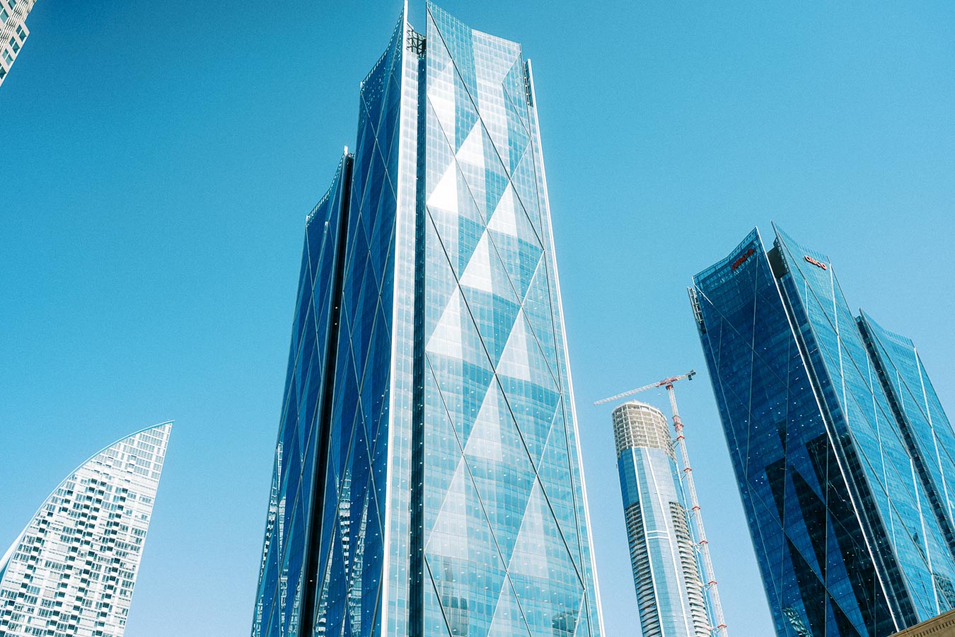 A cluster of modern glass skyscrapers in downtown Toronto with a clear blue sky in the background.