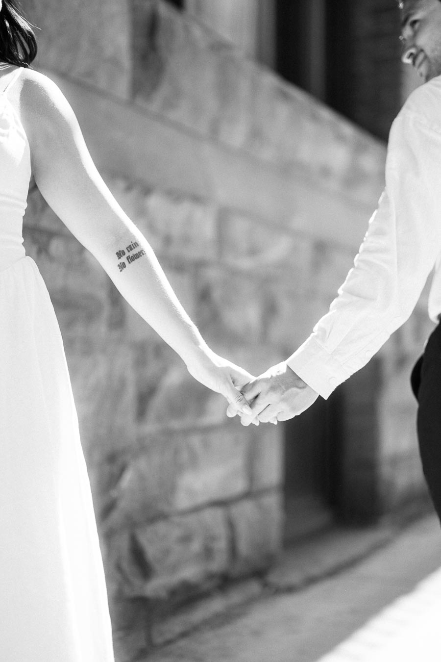 Close-up of Cassie and Gabriel holding hands during their engagement session in downtown Toronto, with sunlight and stone architecture in the background.