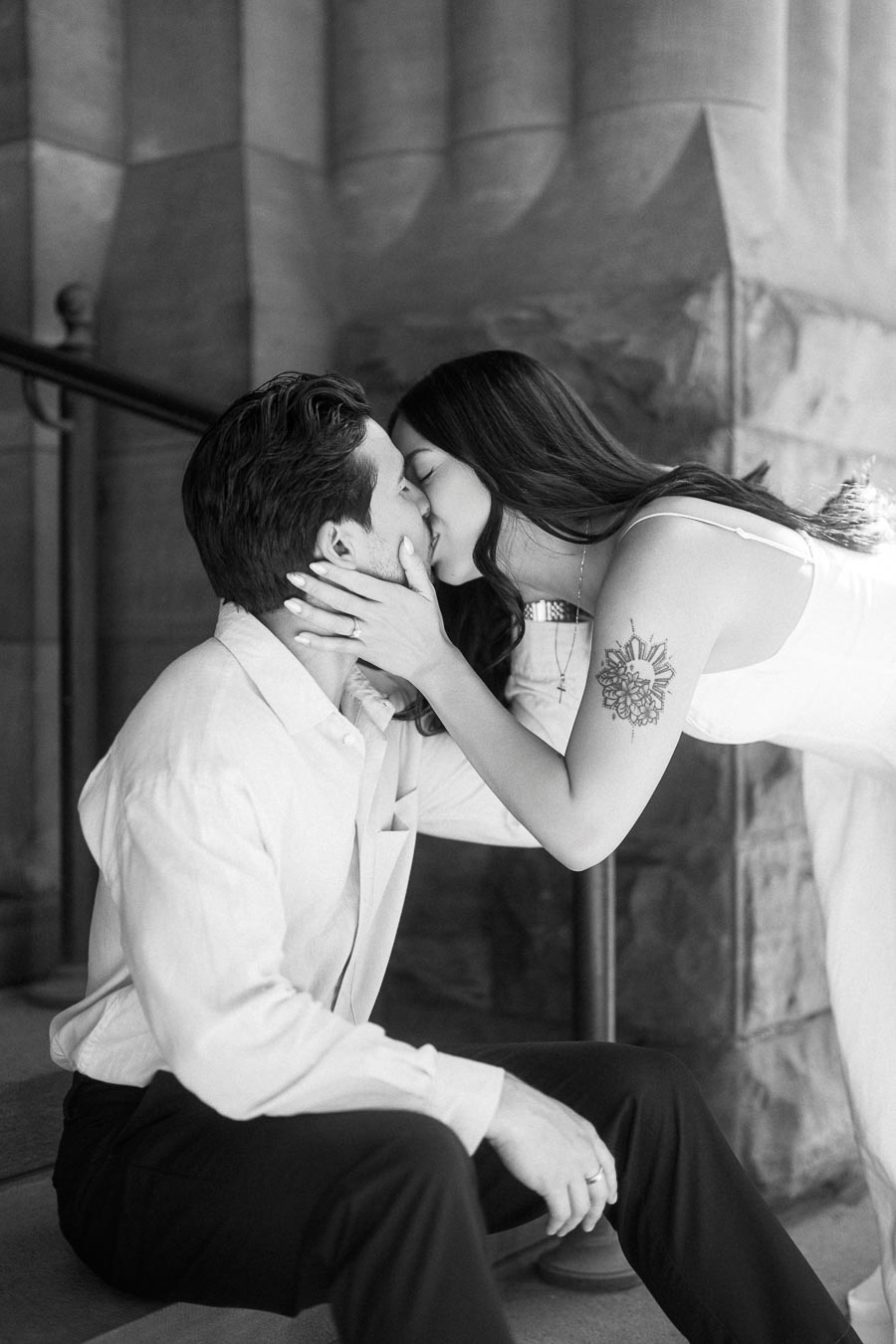 Cassie and Gabriel kissing on the stone steps of a historic building during their engagement session in downtown Toronto.