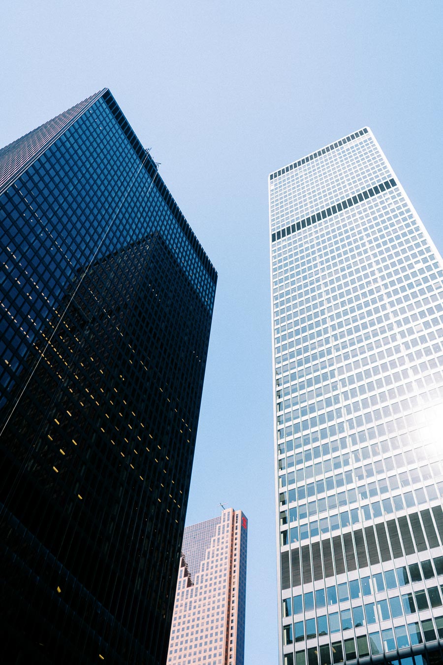 Tall office towers and skyscrapers in downtown Toronto photographed from below, set against a clear blue sky.