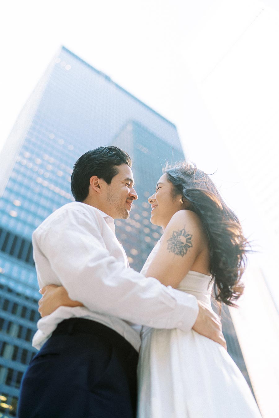 Cassie and Gabriel smiling at each other while embracing, with tall glass office buildings in downtown Toronto visible in the background.