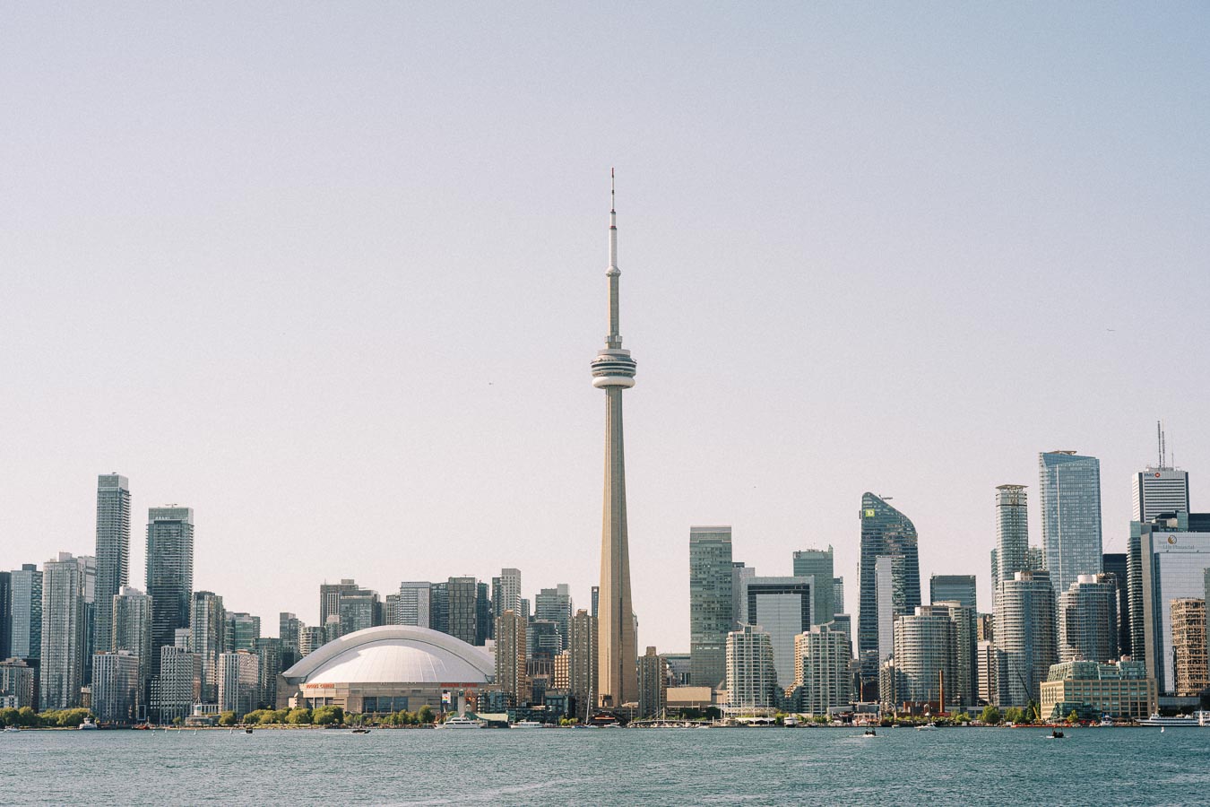 Toronto skyline with the CN Tower and Rogers Centre visible across the water on a sunny day.