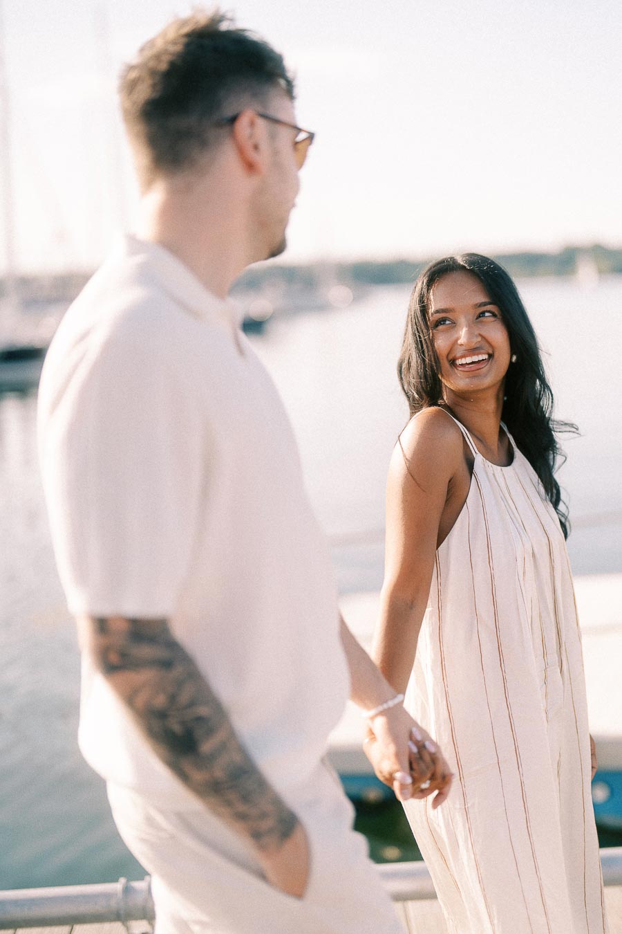 Amber and Devin holding hands by the marina during a golden hour engagement session.