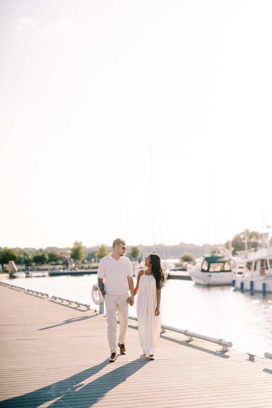 Amber and Devin walking hand in hand on a marina dock at Royal Hamilton Yacht Club.