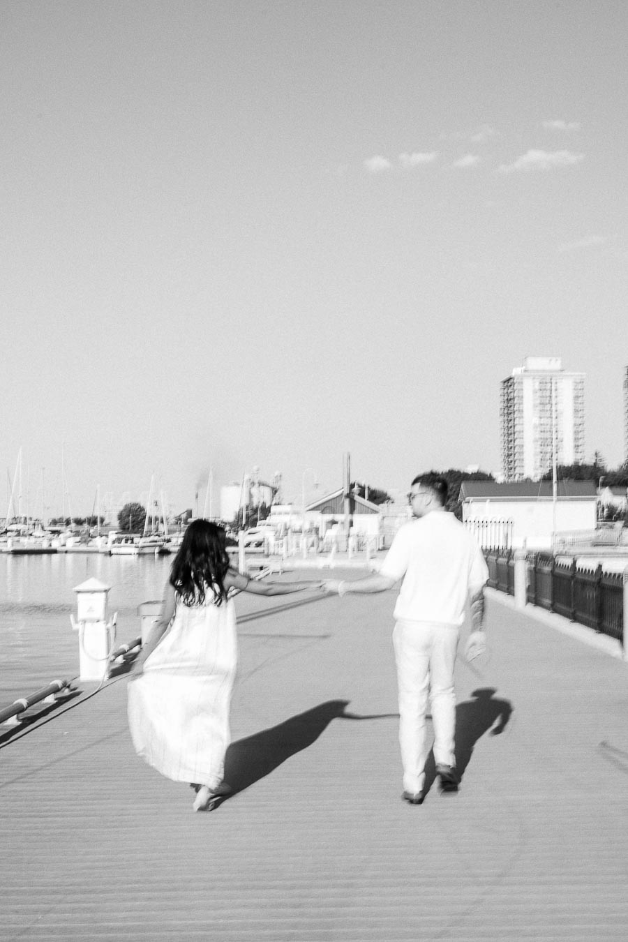 Amber and Devin walking hand in hand on a marina dock at Royal Hamilton Yacht Club.