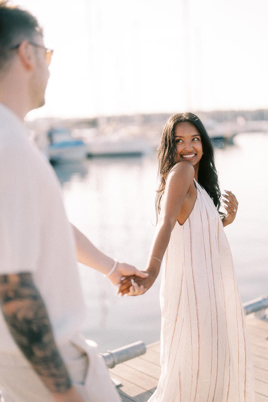 Amber smiles back while holding Devin’s hand on a sunny marina dock in Hamilton, Ontario.