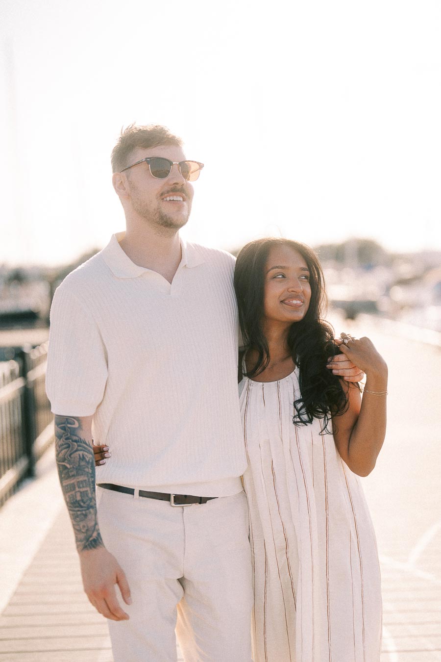 Amber and Devin walking together on a sunlit marina dock in Hamilton, Ontario.