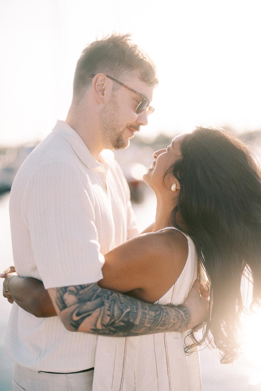 Amber and Devin embrace in warm sunset light during their waterfront engagement session in Hamilton.