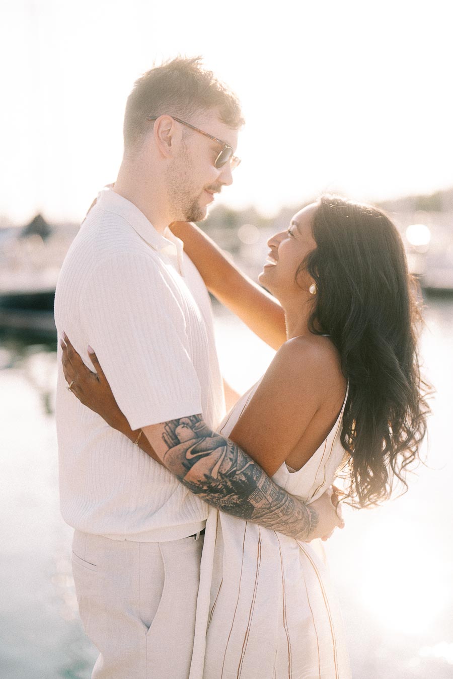 Amber and Devin embrace by the marina in soft golden hour light at Royal Hamilton Yacht Club.