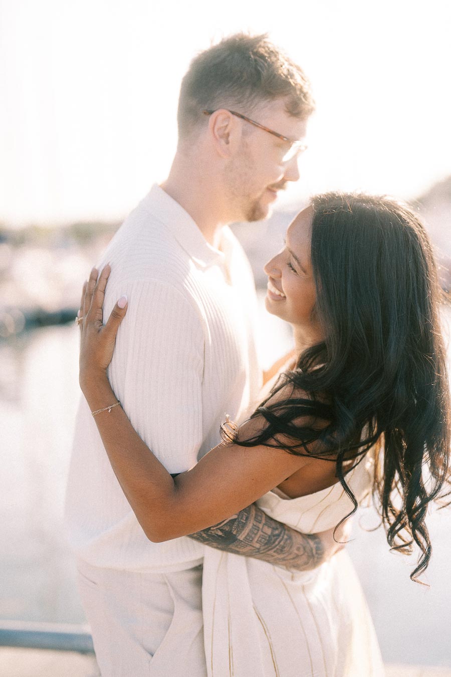 Amber and Devin embracing at a sunlit marina during their Hamilton engagement session.