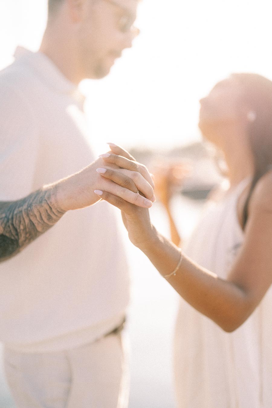 Close-up of Amber and Devin holding hands in soft sunset light during their marina engagement session.