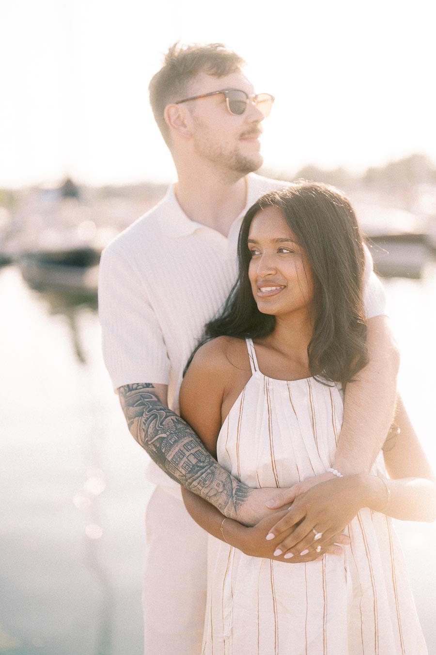 Amber and Devin embracing at a marina during a soft golden hour engagement portrait.
