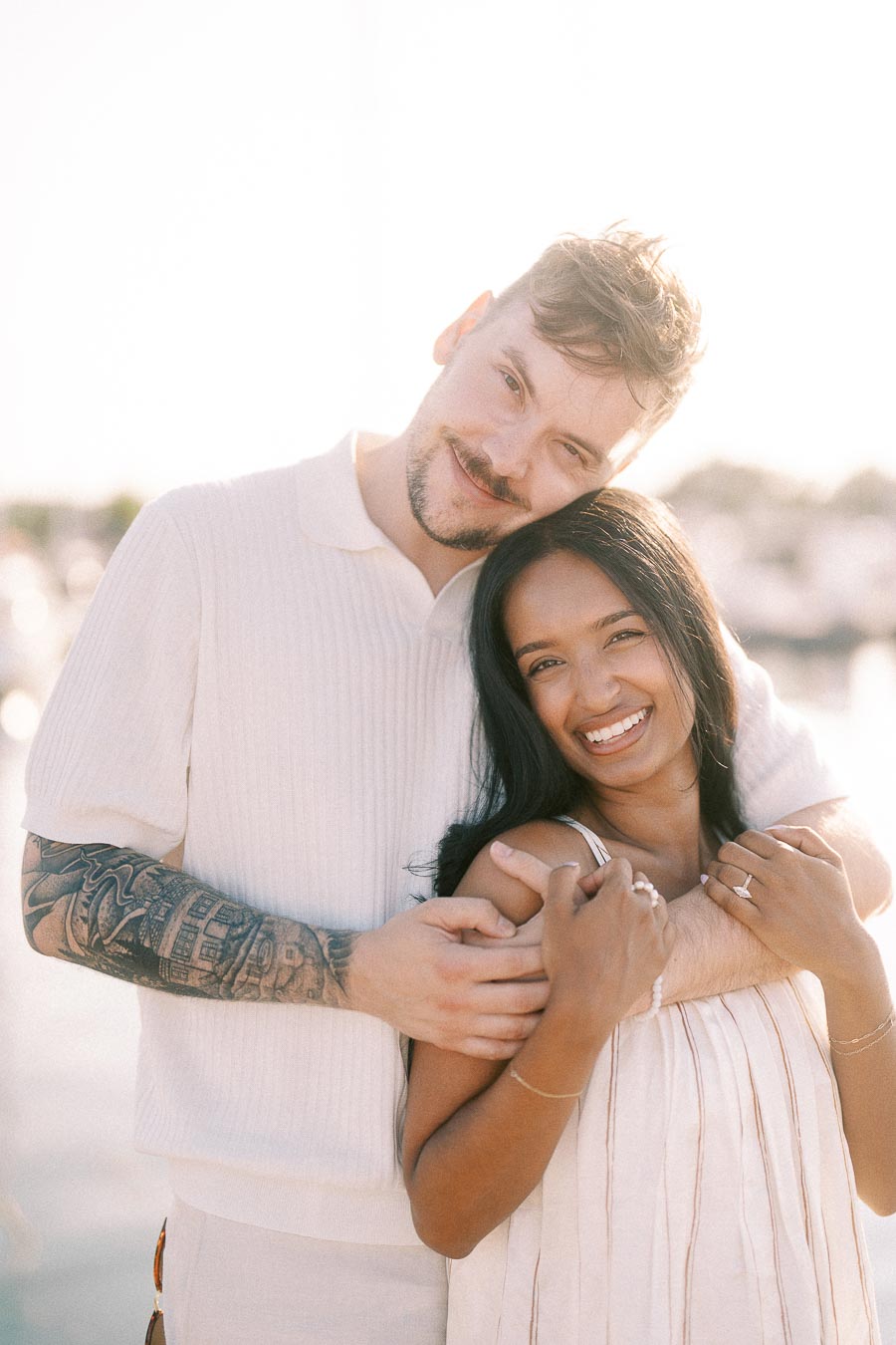 Amber and Devin smiling together in soft golden-hour light at the Hamilton marina.