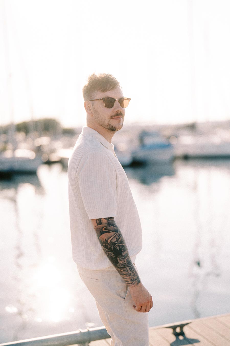 Devin wearing sunglasses on a marina dock during a golden hour engagement session in Hamilton, Ontario.