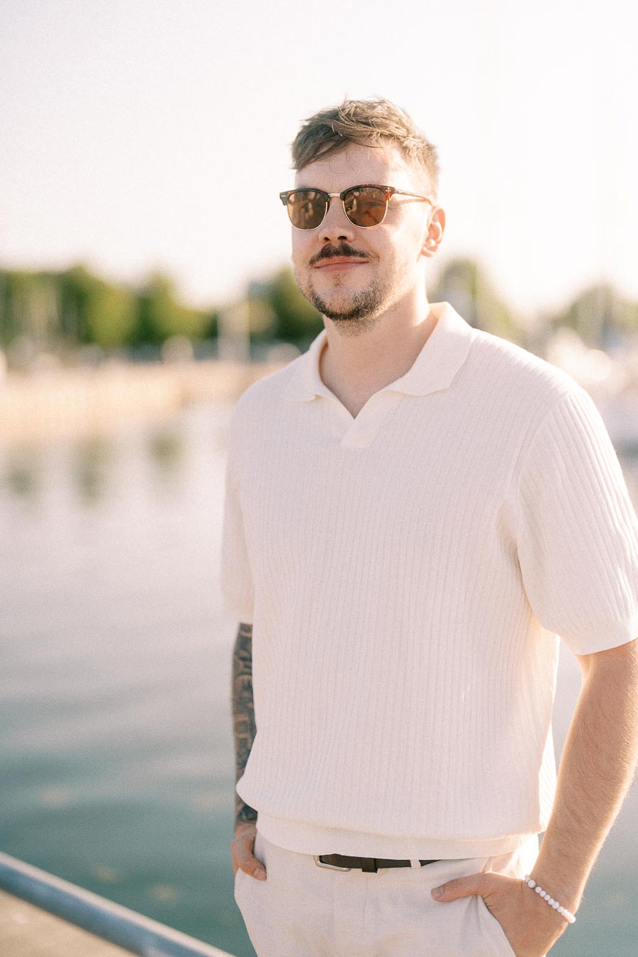 Devin in sunglasses poses by the marina during golden hour in Hamilton, Ontario.
