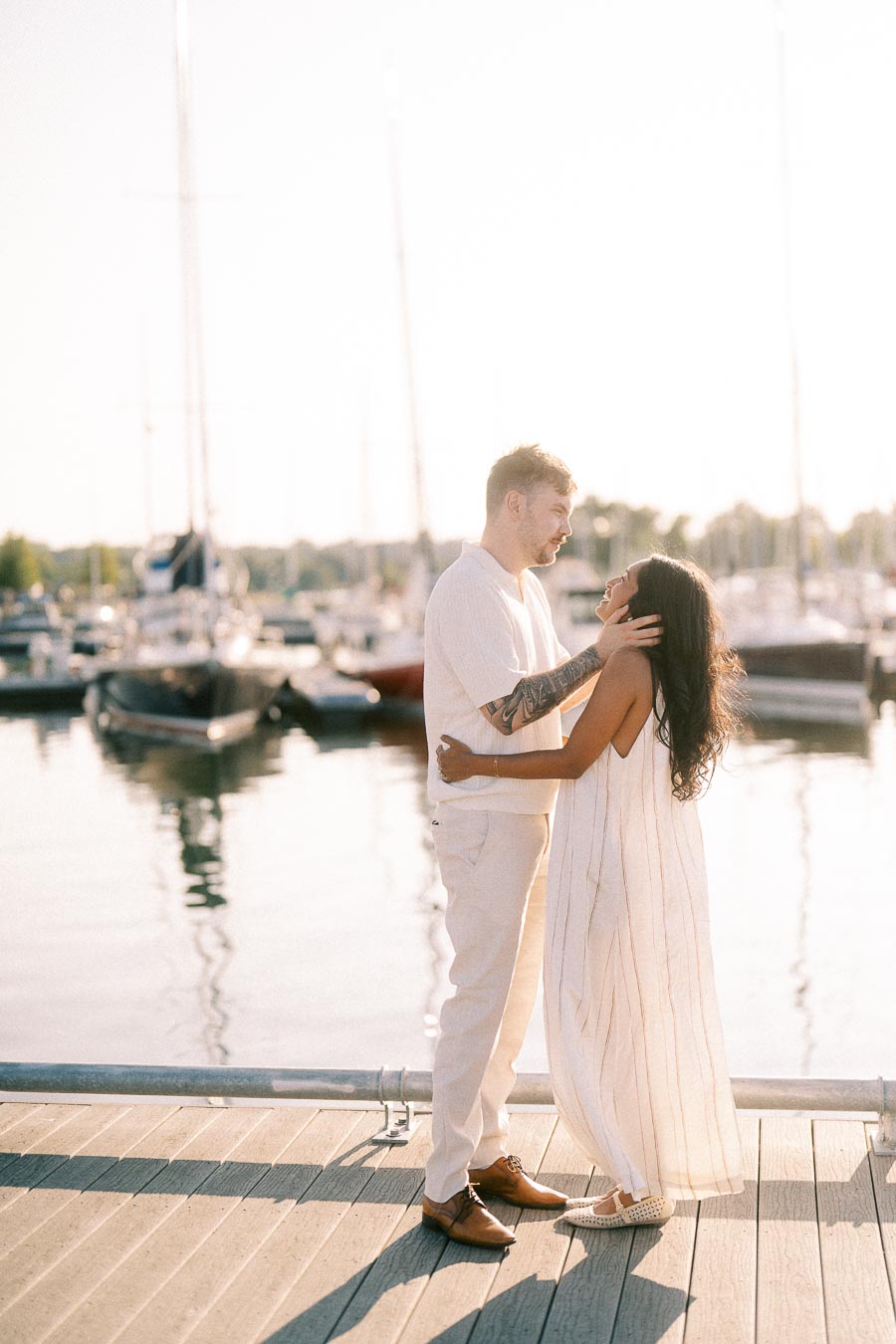 Amber and Devin embrace on a marina dock at golden hour in Hamilton, Ontario.