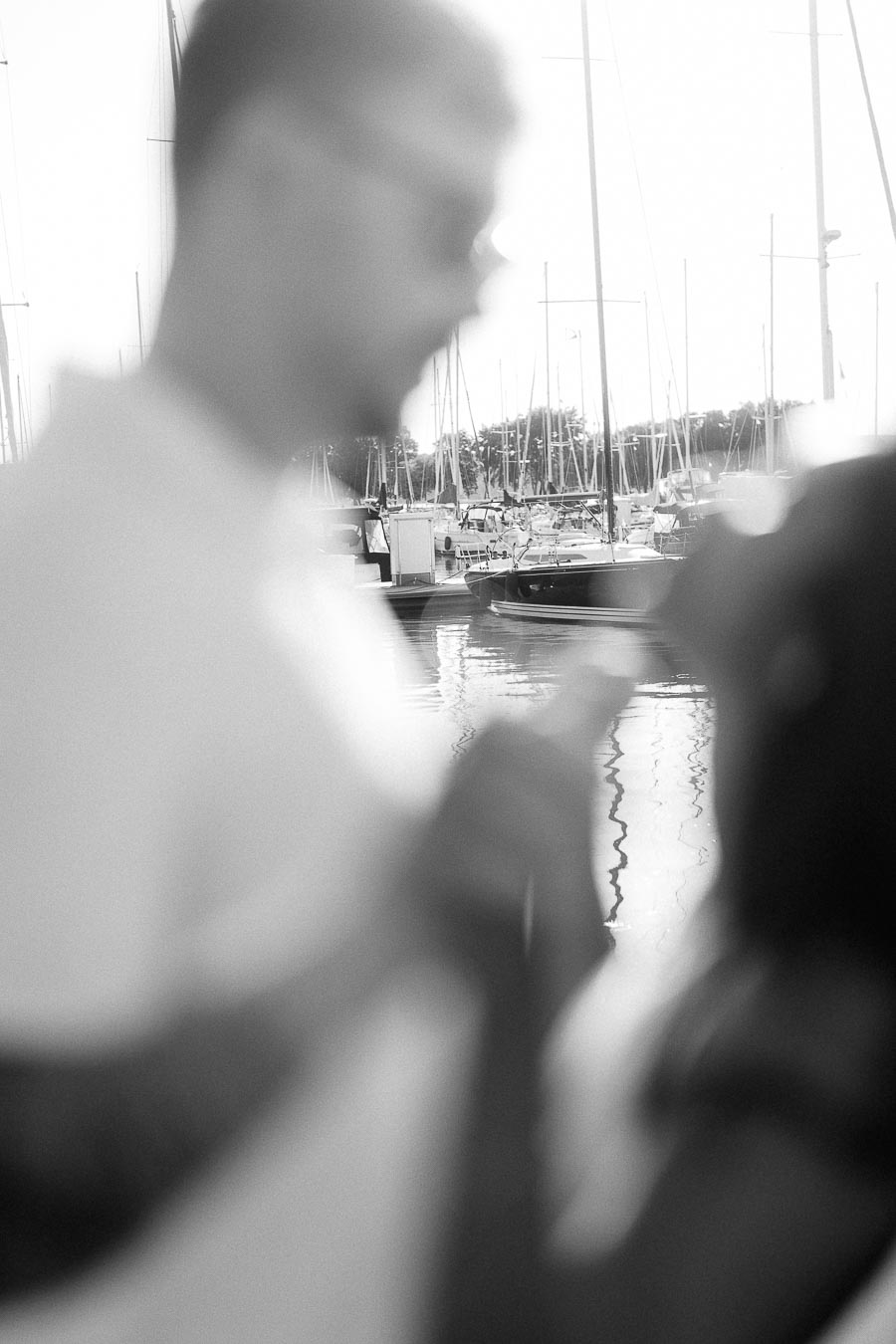 Blurred black-and-white portrait of Amber and Devin by sailboats at Royal Hamilton Yacht Club.