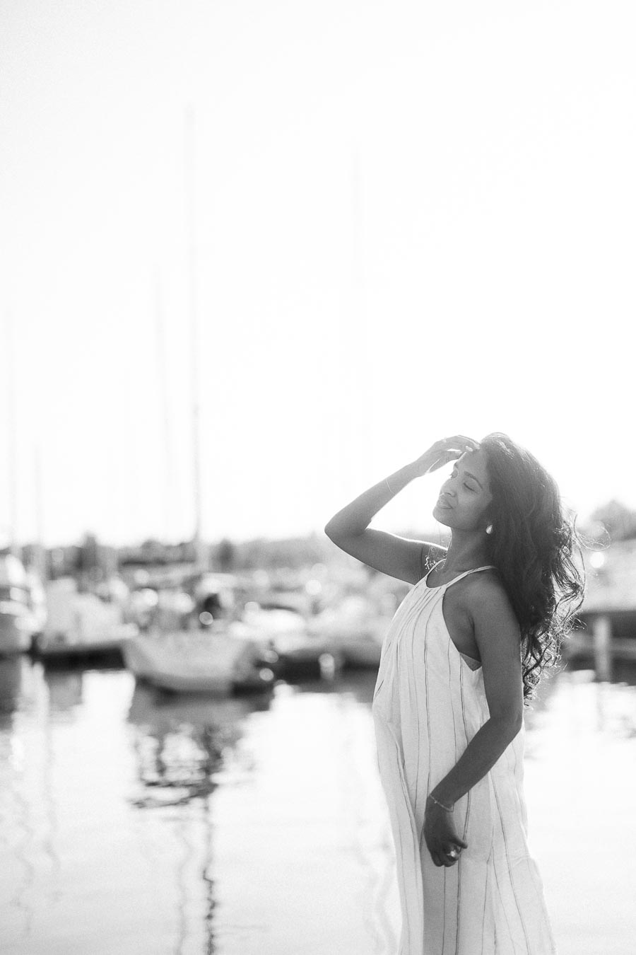 Woman in a white dress posing by sailboats at Royal Hamilton Yacht Club marina.