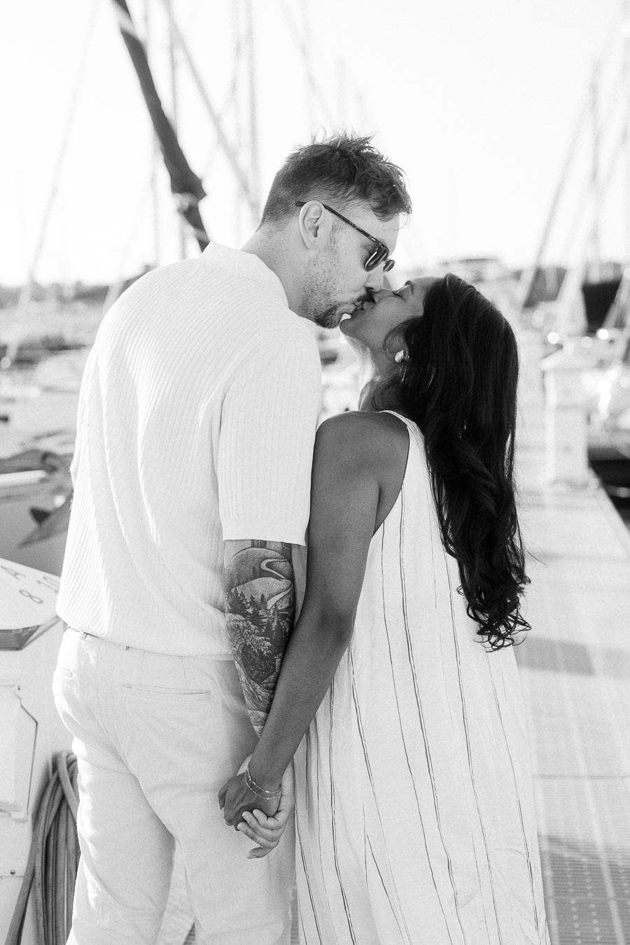 Amber and Devin kissing on a marina dock during their sailboat engagement session in Hamilton, Ontario.