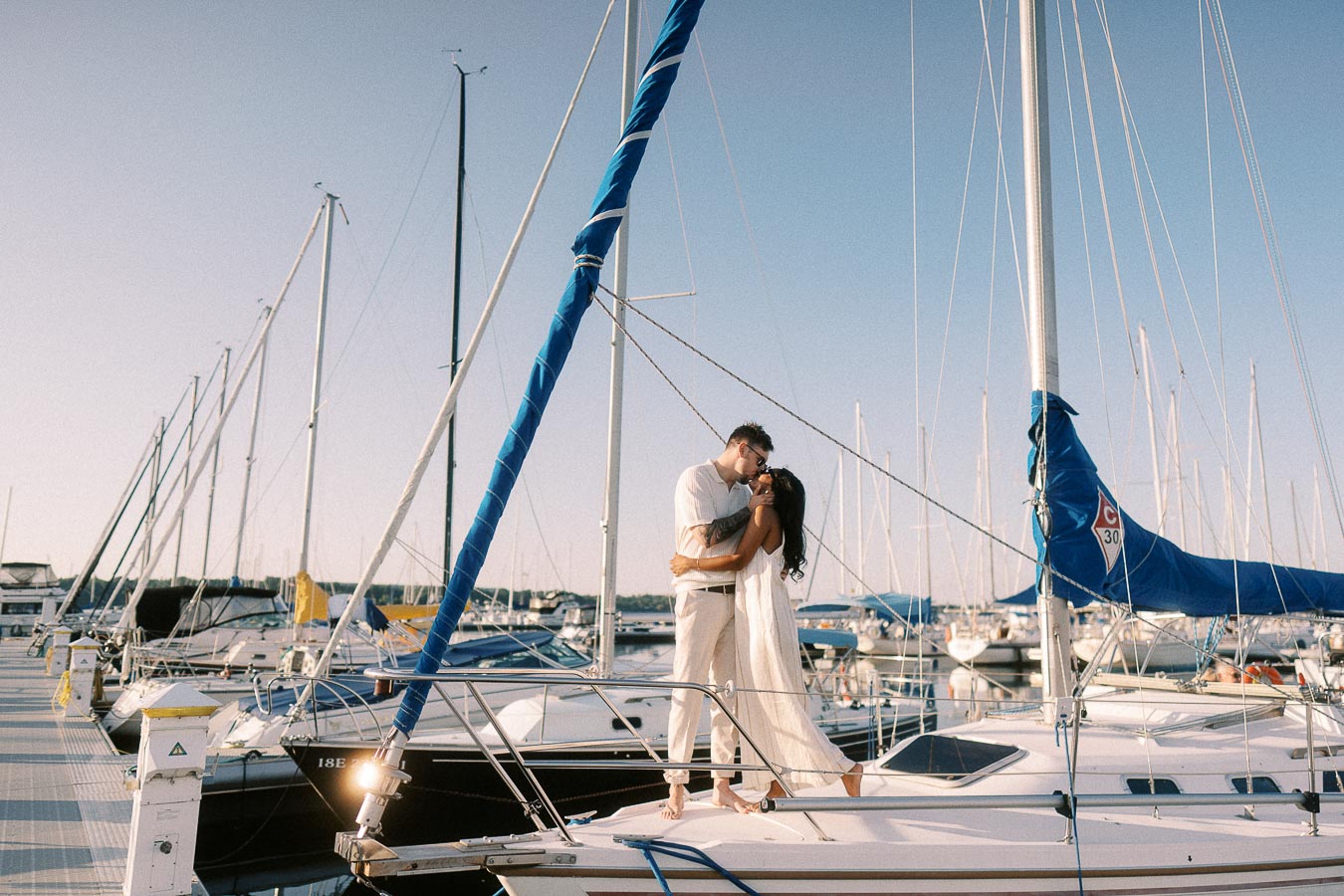 Amber and Devin kiss on a sailboat at Royal Hamilton Yacht Club marina.